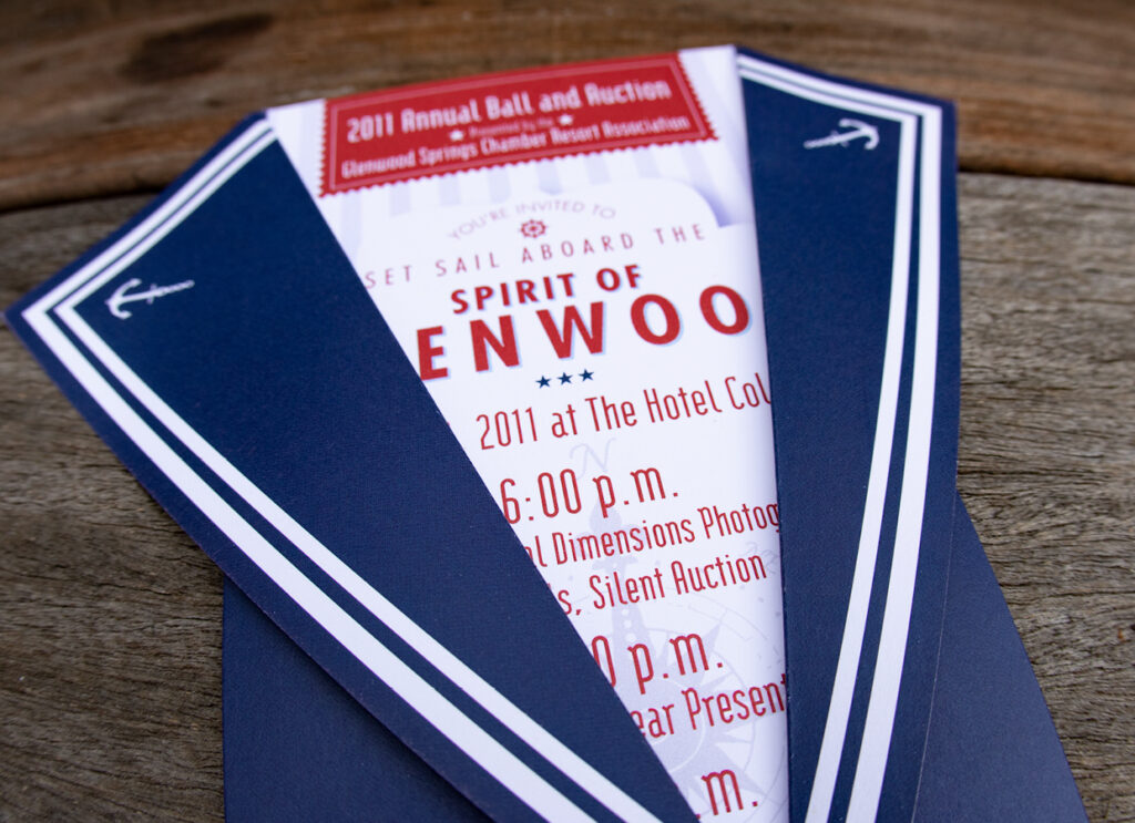 Paper invite that is the shape of a sailor suit, in the color of blue and red, and words about the annual ball are written on the inside