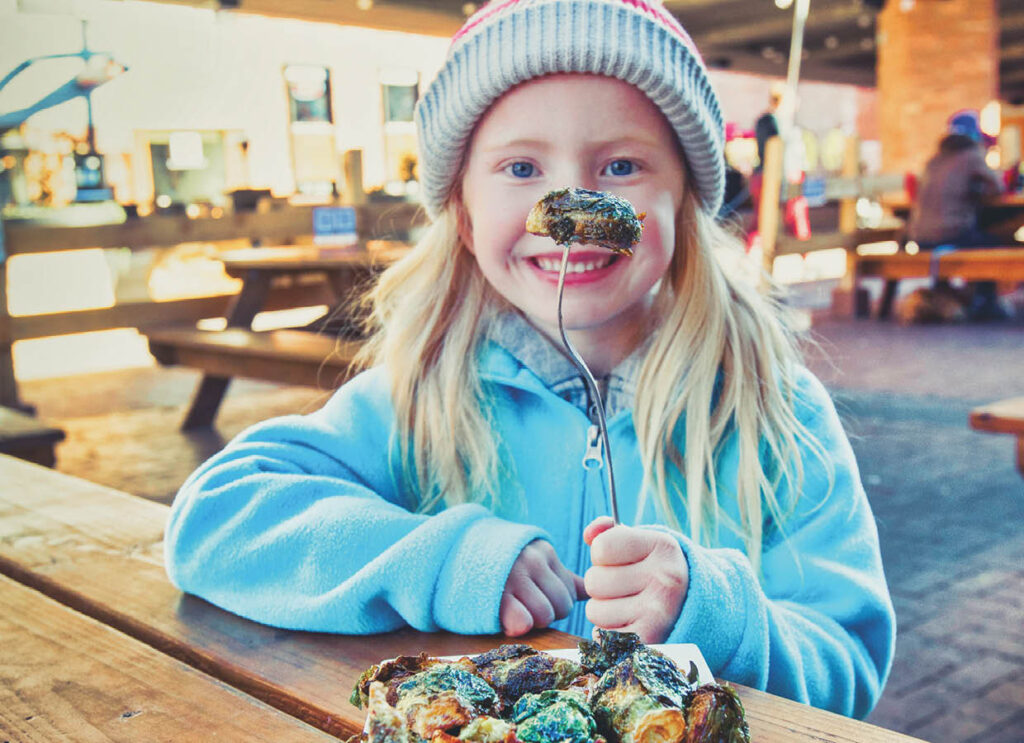 cute girl at a restaurant with brussel sprouts