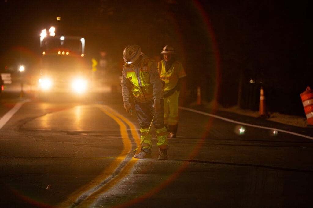 two construction men inspecting the line painting in the nighttime 